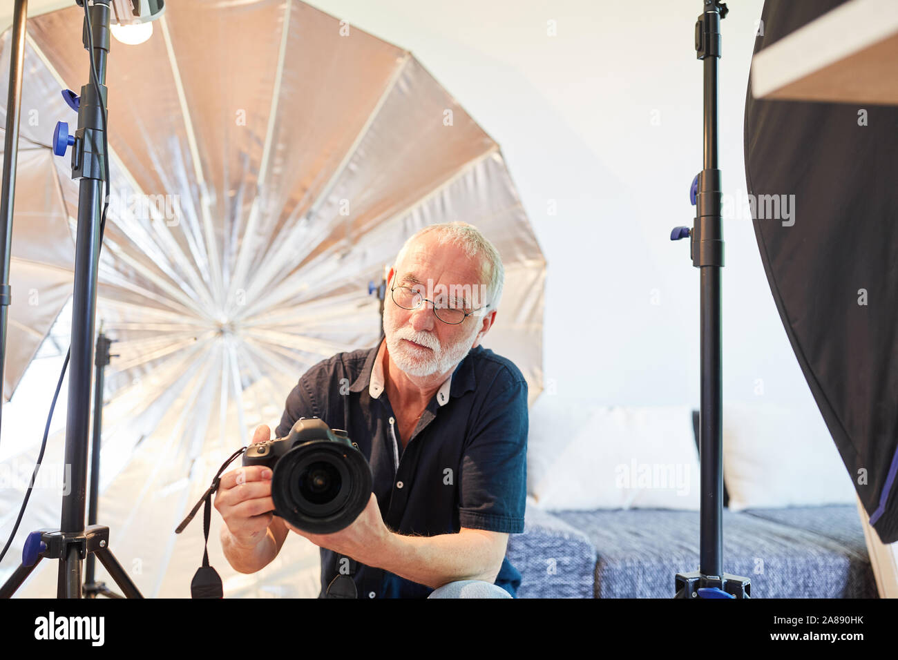 Photographe senior professionnel avec appareil photo numérique dans son studio photo Banque D'Images