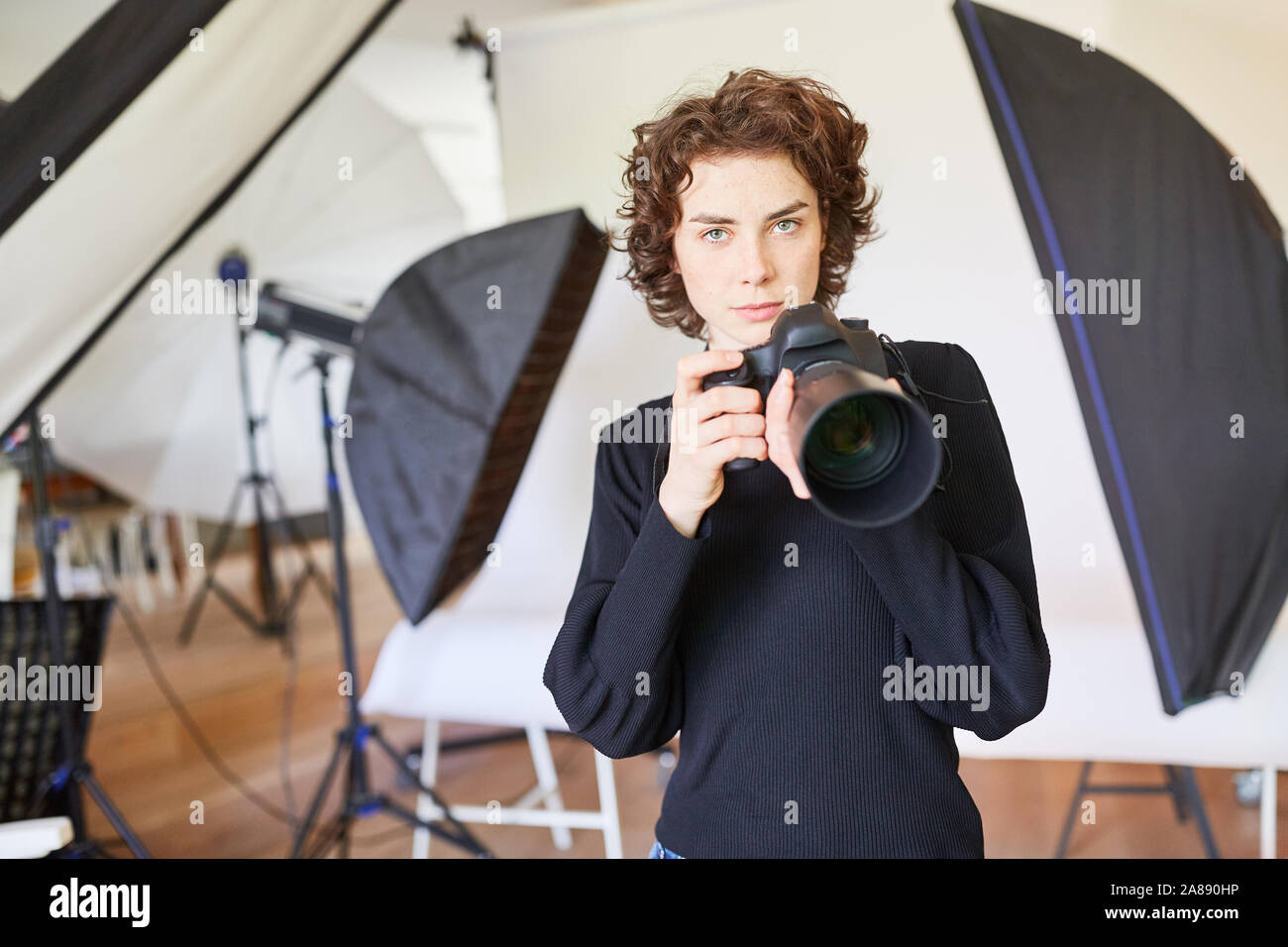 Confiant le jeune photographe avec appareil photo numérique dans la photo studio Banque D'Images