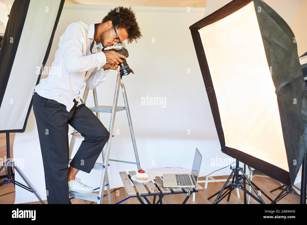 Photographe alimentaire avec caméra à la séance photo dans le studio sur une échelle Banque D'Images