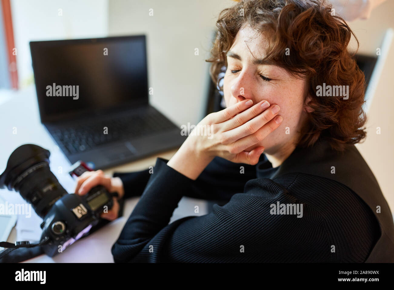 Fatigué photographe avec appareil photo numérique et un ordinateur portable à 24 Banque D'Images