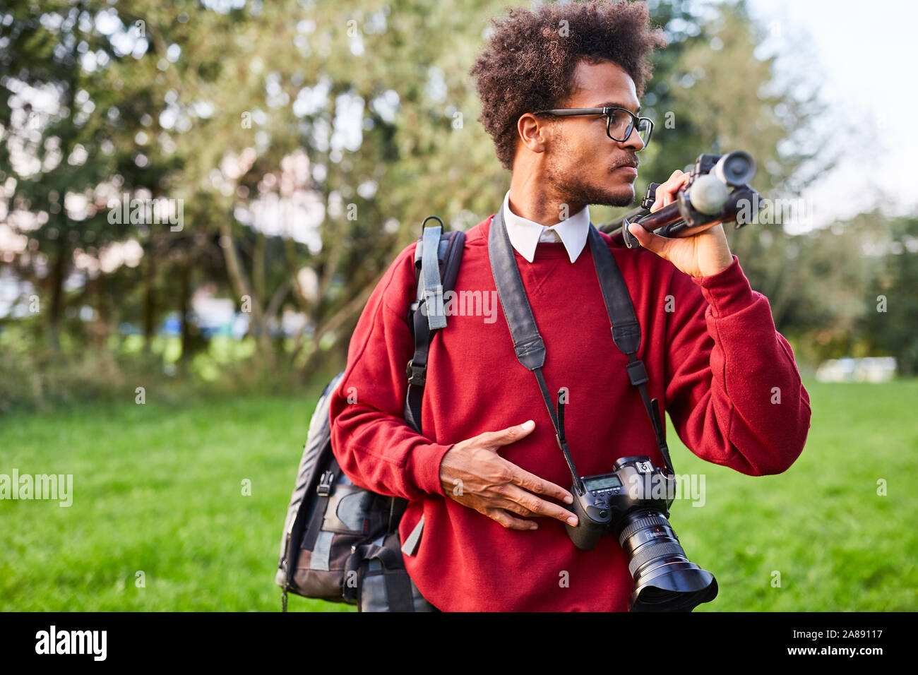 Jeune homme comme un photographe professionnel avec l'appareil photo et le trépied dans la nature Banque D'Images