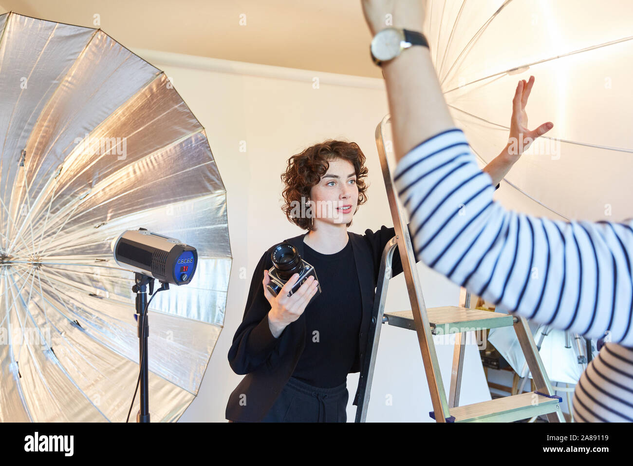 Le jeune photographe avec appareil photo de format moyen en face de l'unité de flash dans le studio photo Banque D'Images