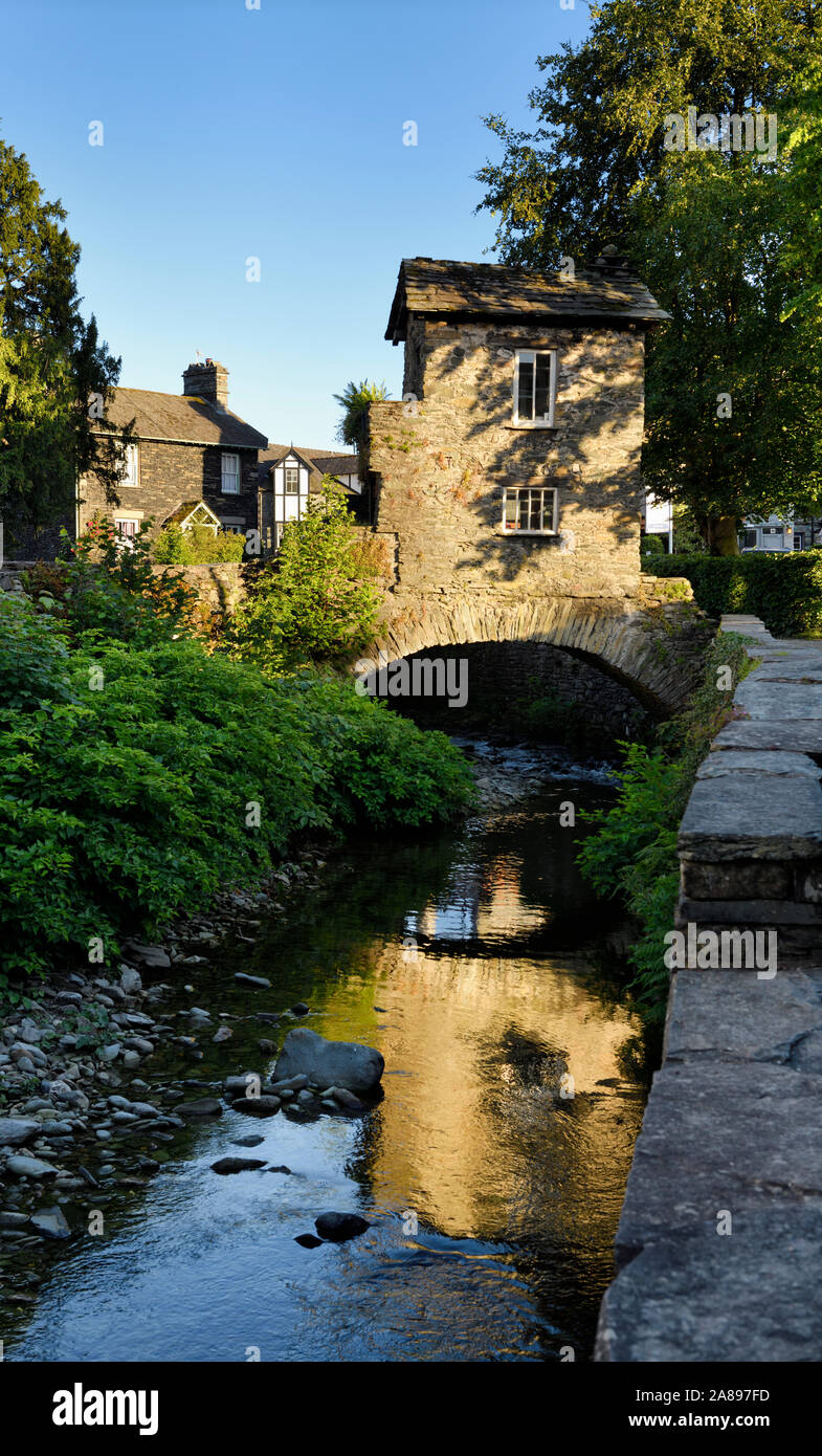 Bridge House stock chevauchant la rivière Beck avec la réflexion de la lumière du soleil du soir à Ambleside Lake District Angleterre Banque D'Images