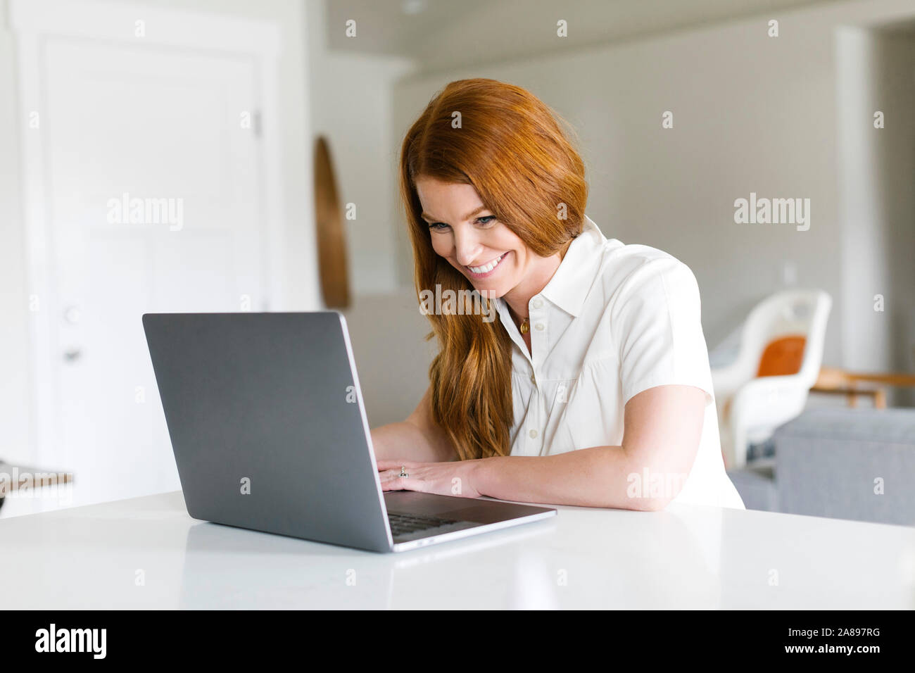 Smiling woman using laptop at home Banque D'Images