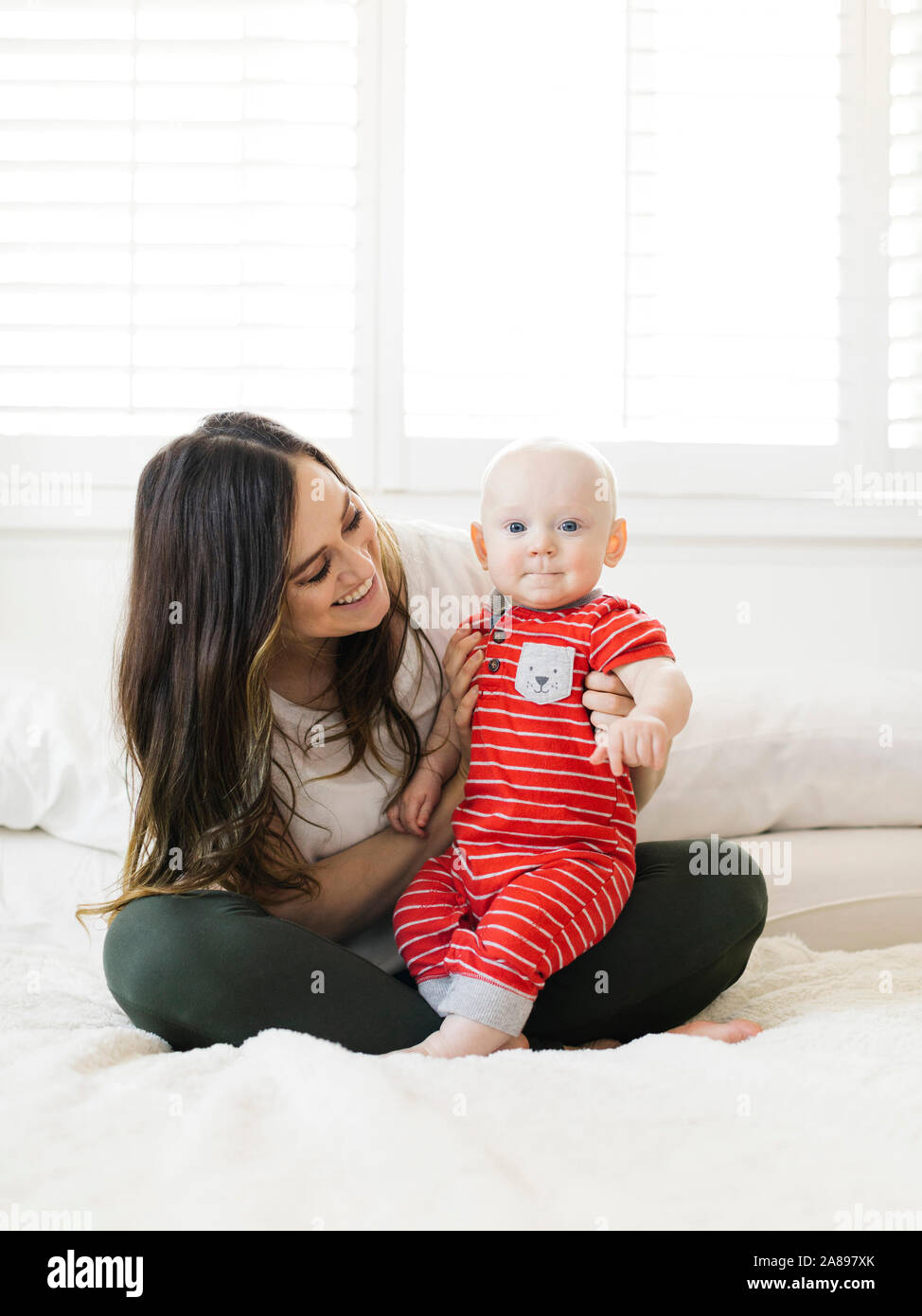 Femme souriante tenant son fils au lit Banque D'Images
