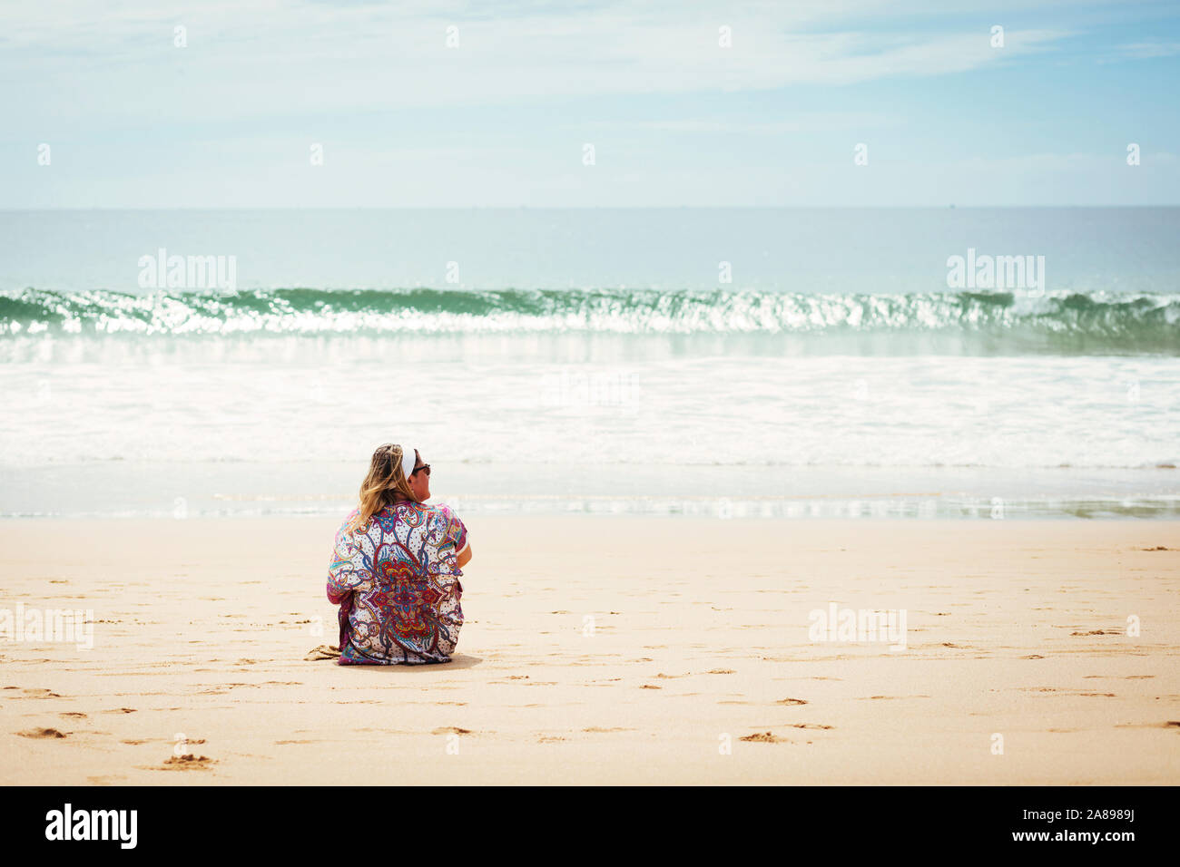 Femme assise sur la plage à Lisbonne, Portugal Banque D'Images