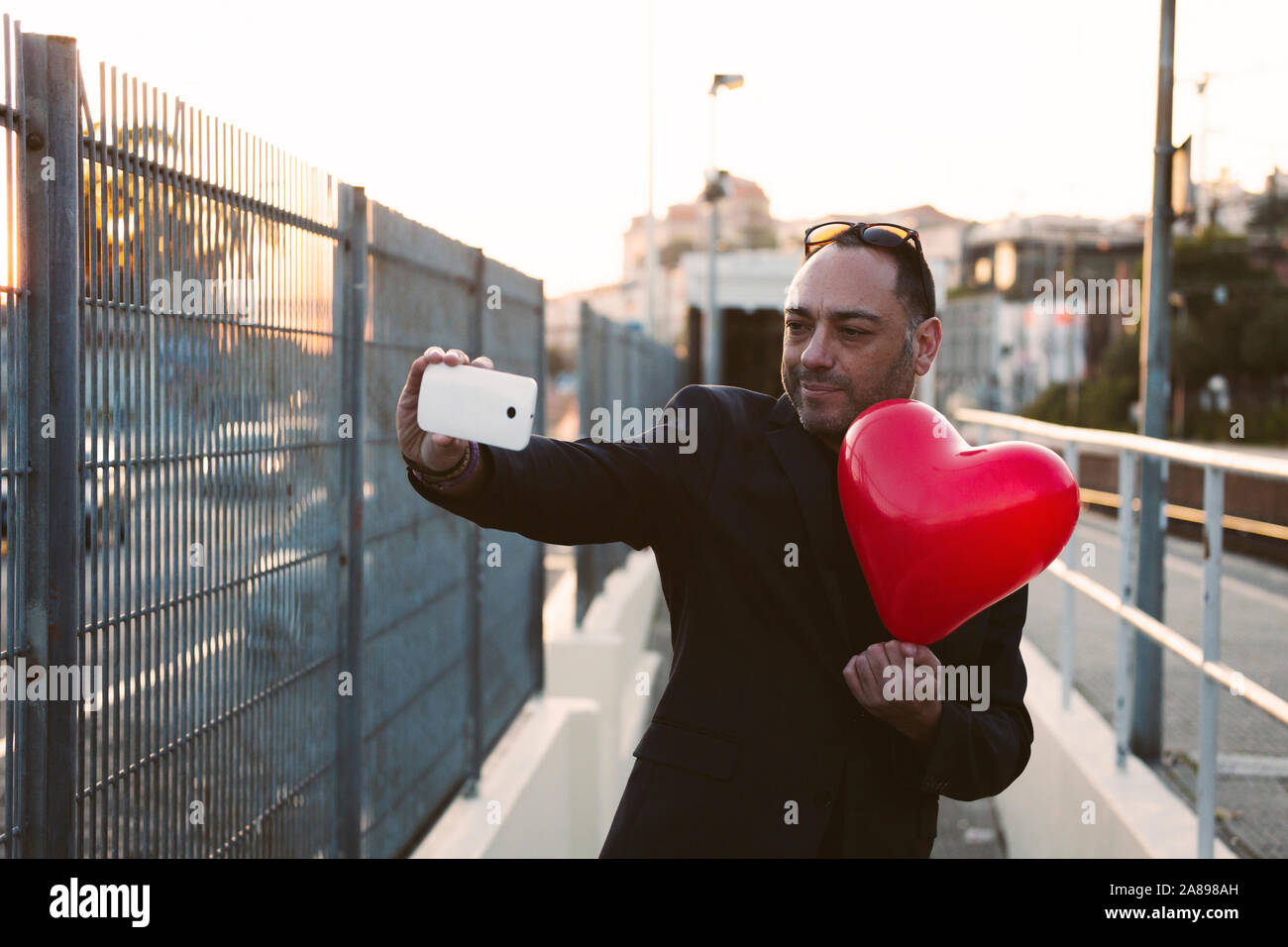 Homme prenant le selfie avec un ballon en forme de cœur rouge Banque D'Images