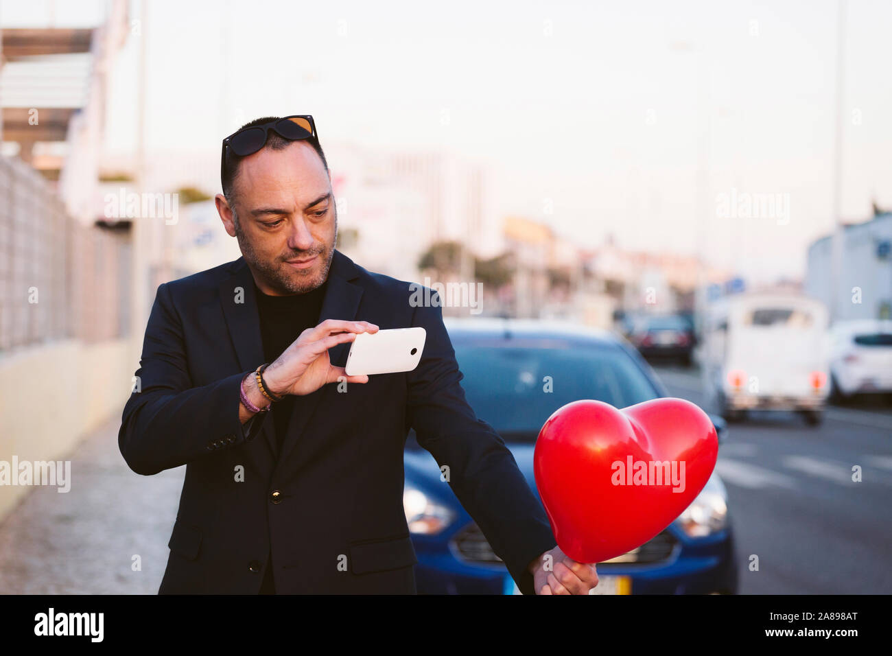 Homme photographiant un ballon en forme de cœur rouge Banque D'Images
