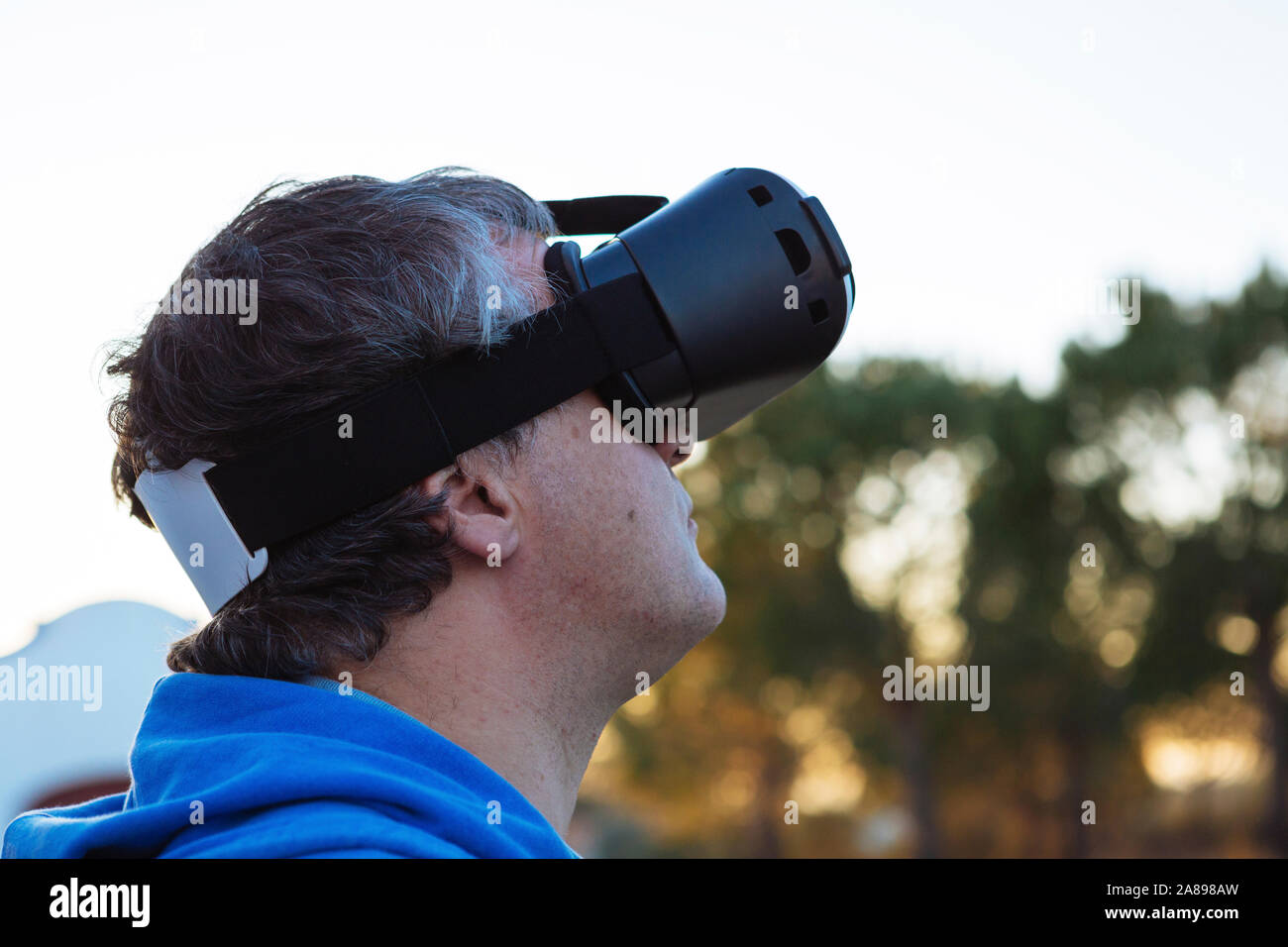 Homme adulte de taille moyenne portant un simulateur de réalité virtuelle à l'extérieur Banque D'Images