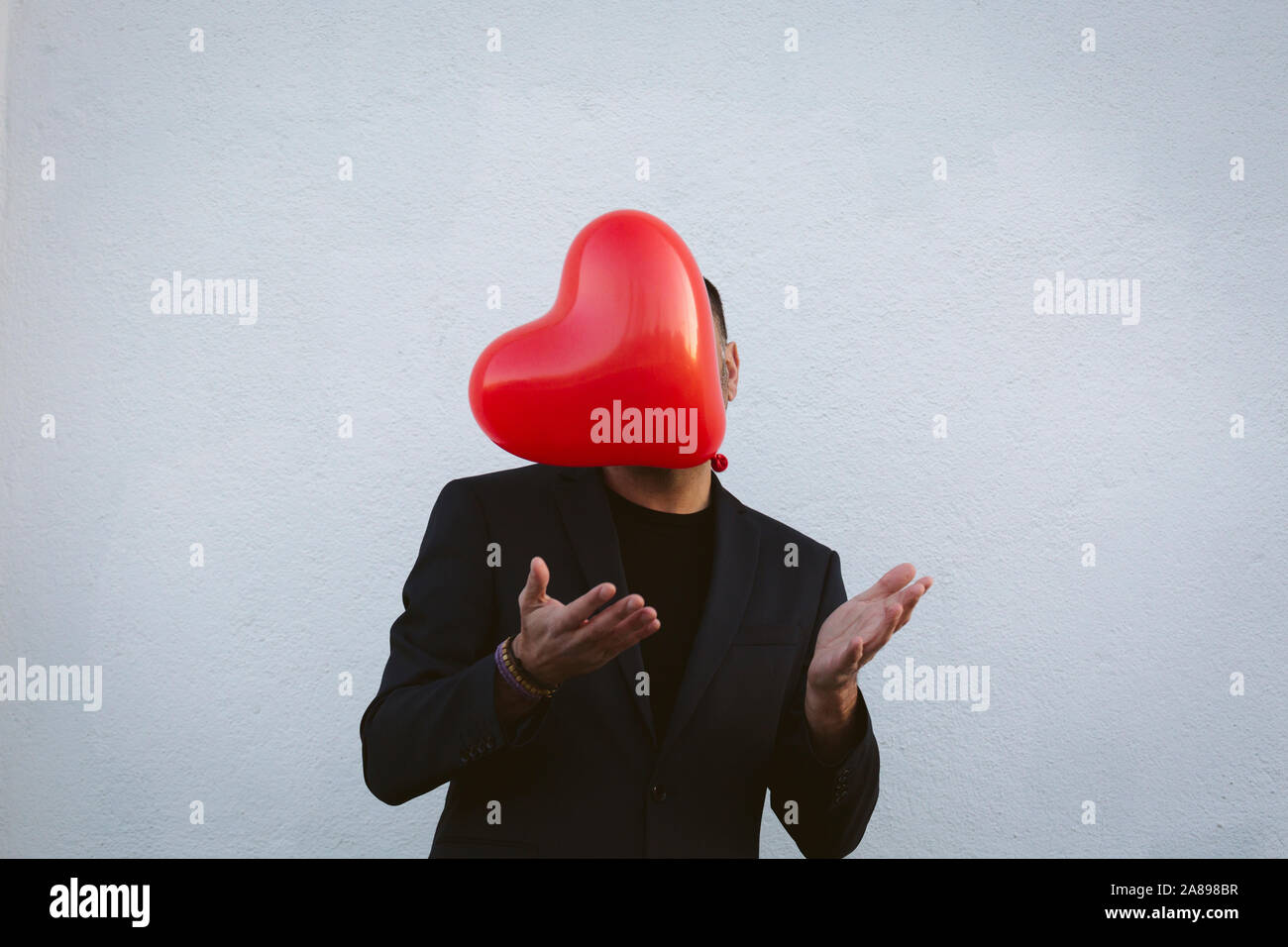 Homme lançant un ballon rouge en forme de coeur Banque D'Images