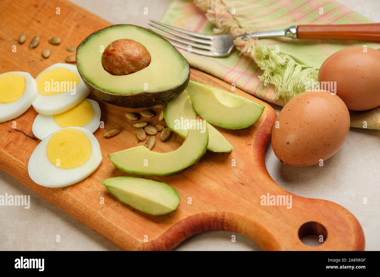 Avocat, œuf et graines de tournesol sur planche à découper Banque D'Images