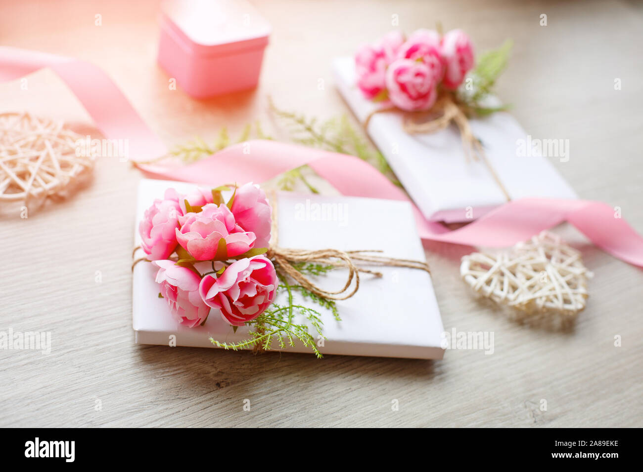 Boîte cadeau blanche enveloppée de papier avec noeud en corde sur fond de bois rustique. Banque D'Images