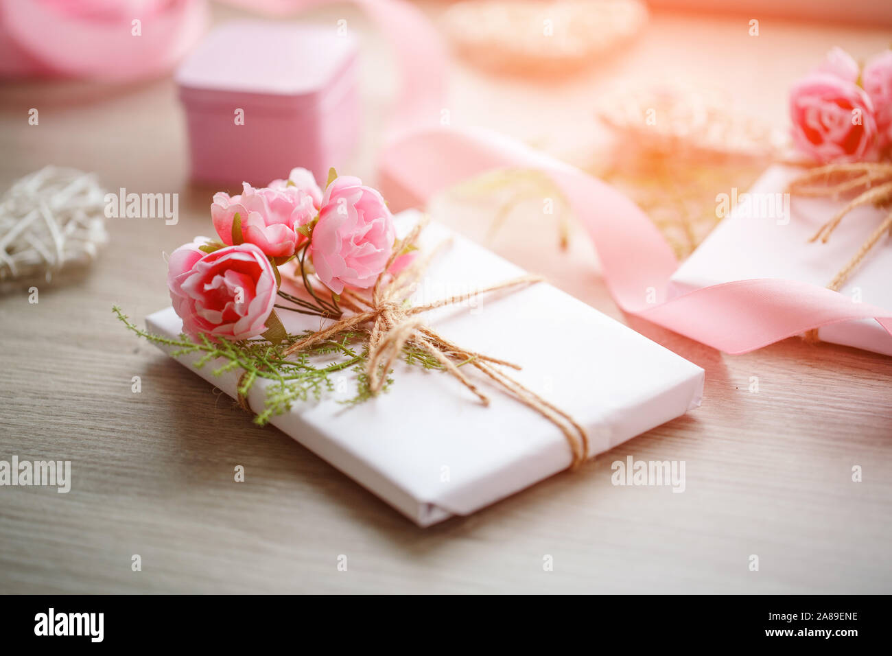 Composition avec boîtes cadeaux décorées de branches vertes et de roses. Banque D'Images