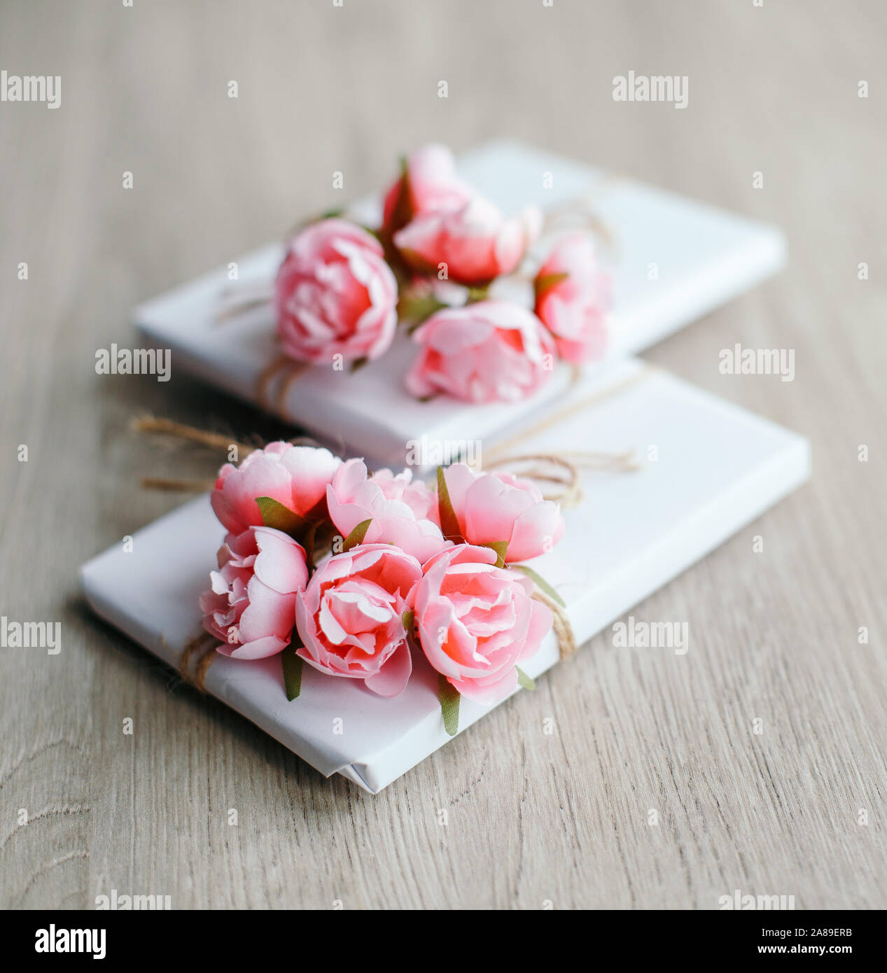 Quelques boîtes cadeau enveloppées de papier blanc artisanal simple et décorées avec un bouquet de roses et un bouquet d'eucalyptus. Banque D'Images