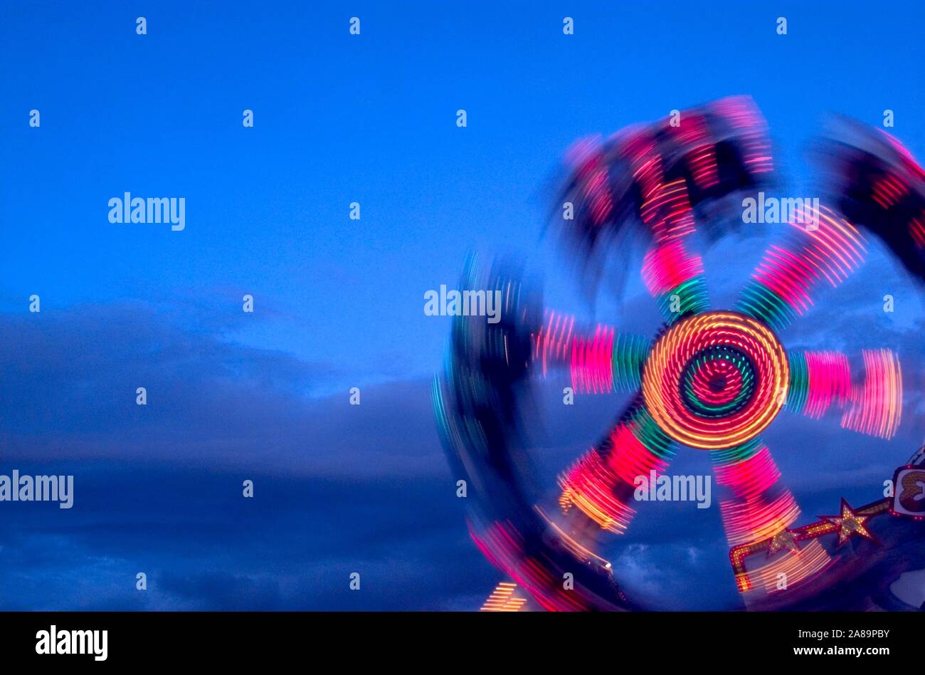 Tourbillonnant, éclairé au néon carnival ride at Dusk Banque D'Images
