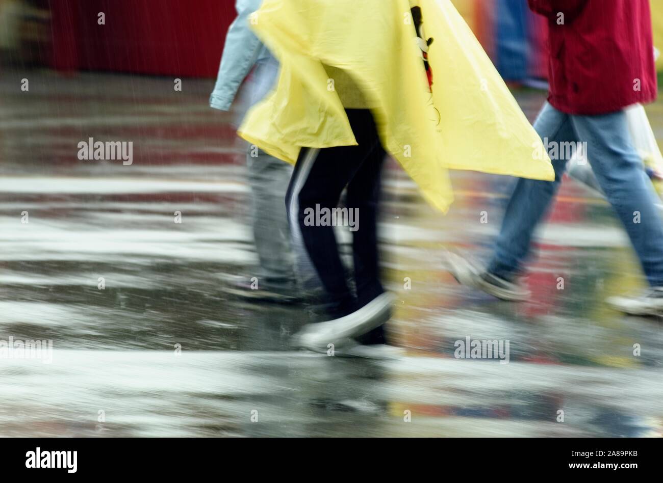 Un groupe de personnes dans l'exécution d'imperméables colorés dans les rues sous la pluie Banque D'Images