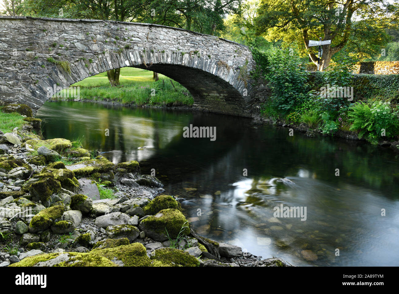 Des roches couvertes de mousse sur les rives du fleuve Rothay à Rydal avec stone arch bridge Pelter Lake District Angleterre Banque D'Images