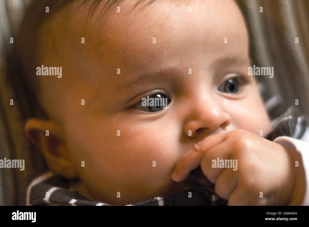Bébé en pleine réflexion, sucer le pouce, bébé repose sur la main. De grands yeux Banque D'Images