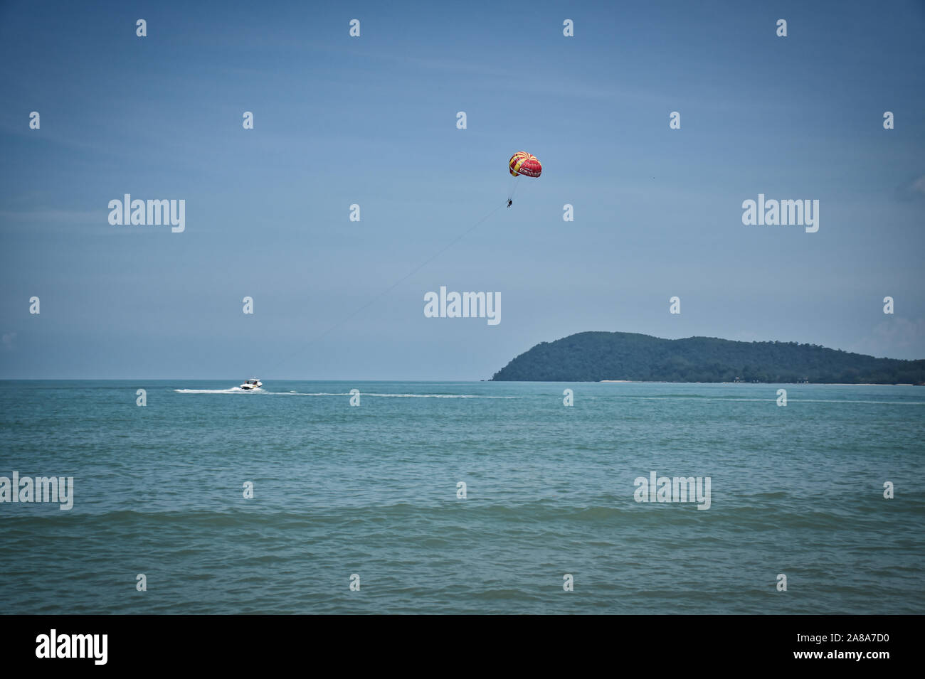 Parapente sur les vagues de la mer d'Andaman azure sous le ciel bleu près des rives de la plage de sable magnifique et de superbes exotiques Cenang à Langka Banque D'Images