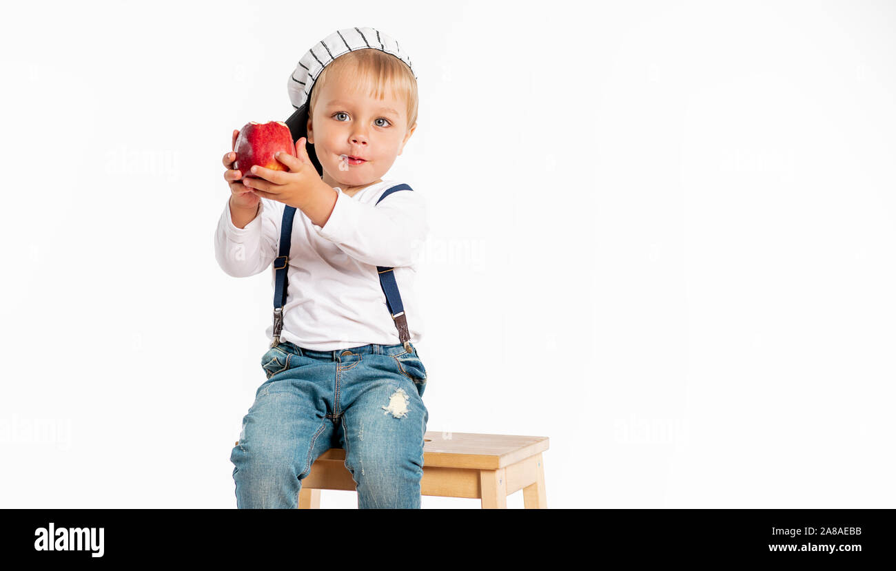Baby Boy eating apple and smiling in studio isolé sur fond blanc. Concept d'aliments frais en bonne santé Banque D'Images