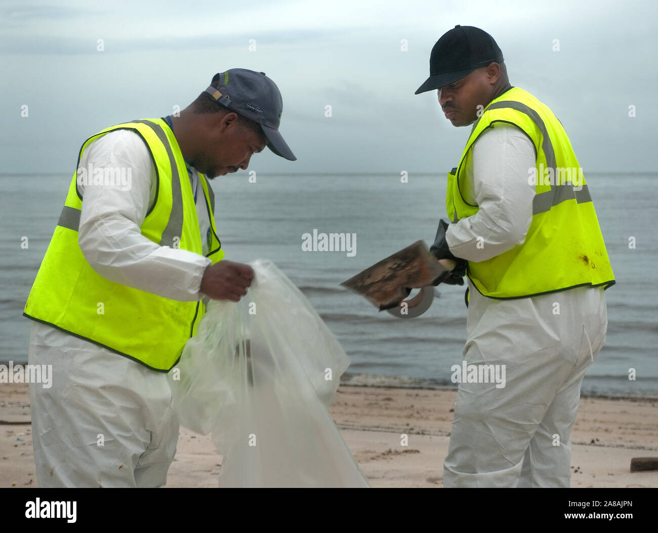 Travailleurs de nettoyage en cas de déversement d'enlever les galettes de goudron de la plage après le déversement de pétrole de BP à Gulfport, Mississippi, le 30 juin 2010. Banque D'Images