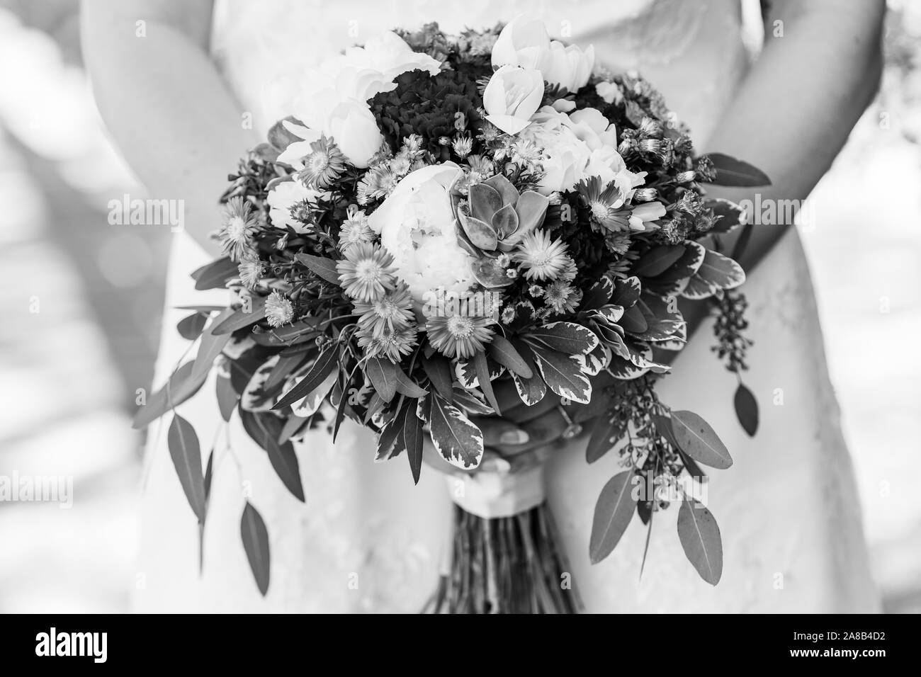 Close up of a bride holding son gros bouquet rempli de diverses fleurs et verdure. Noir et blanc. Banque D'Images