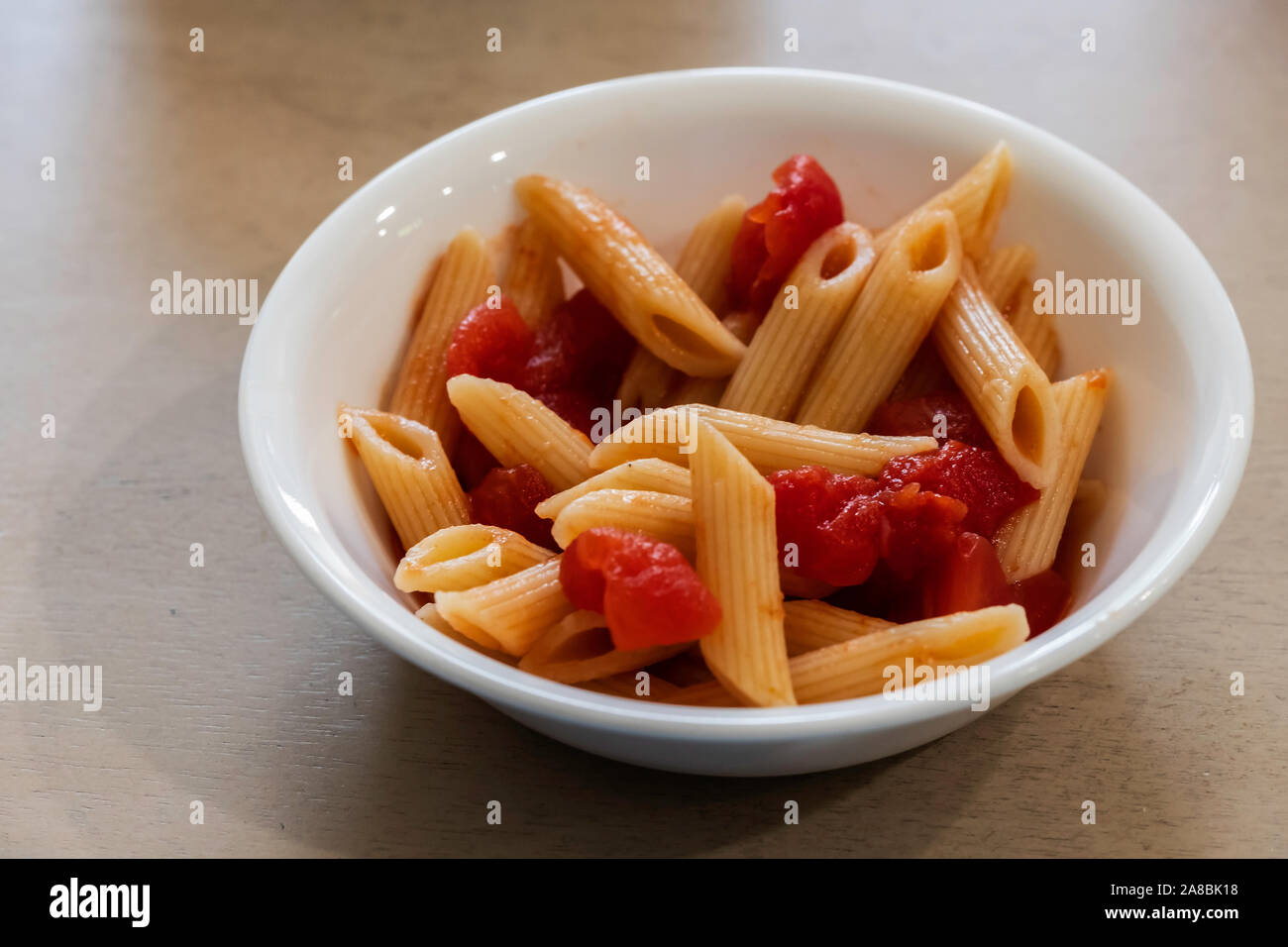 Pennes cuits et les tomates dans un petit bol blanc. Banque D'Images