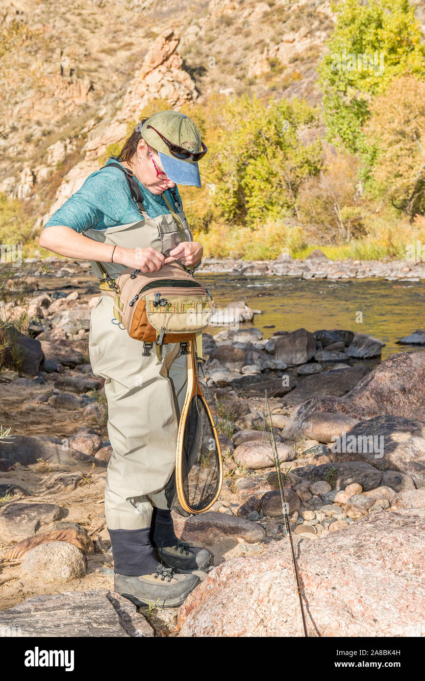 Une femme prépare sa canne à pêche avec la ligne et d'un crochet qu'elle dirige sur la Powder River pour un après-midi de pêche. Banque D'Images