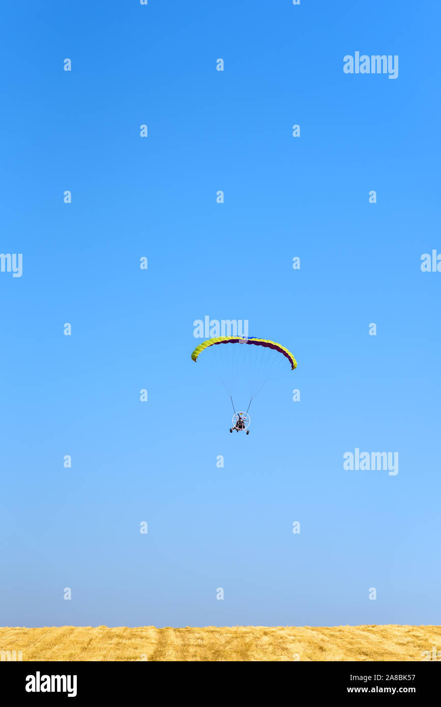 Powered parachute parapente sur fond de ciel bleu et sur fond jaune. Vol paramoteur en journée ensoleillée. La liberté et des vacances d'concept, sport extrême. Banque D'Images