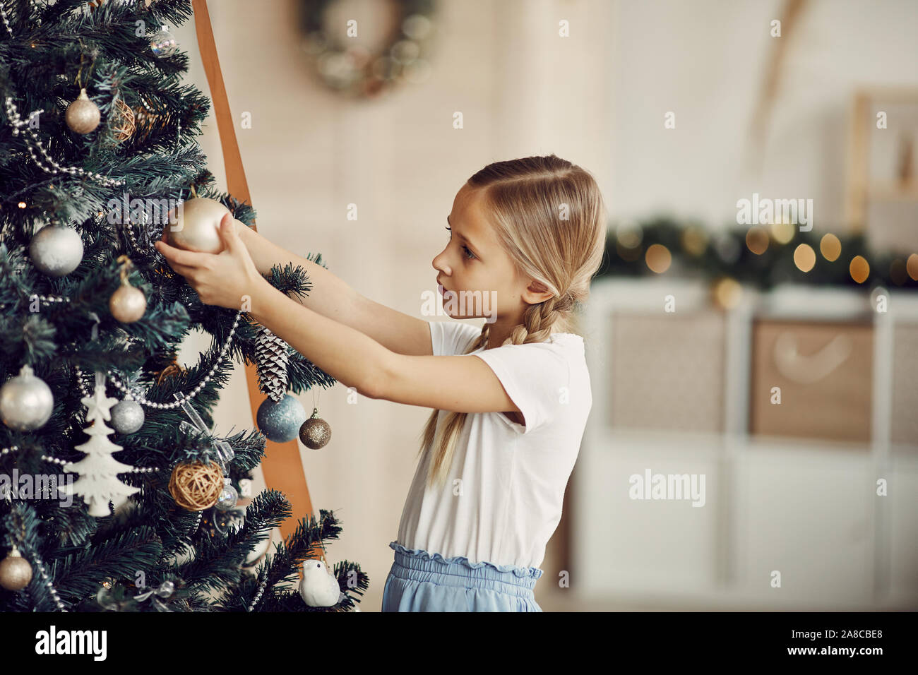 Cute little girl et l'examen de beaux jouets sur arbre de Noël à la maison Banque D'Images