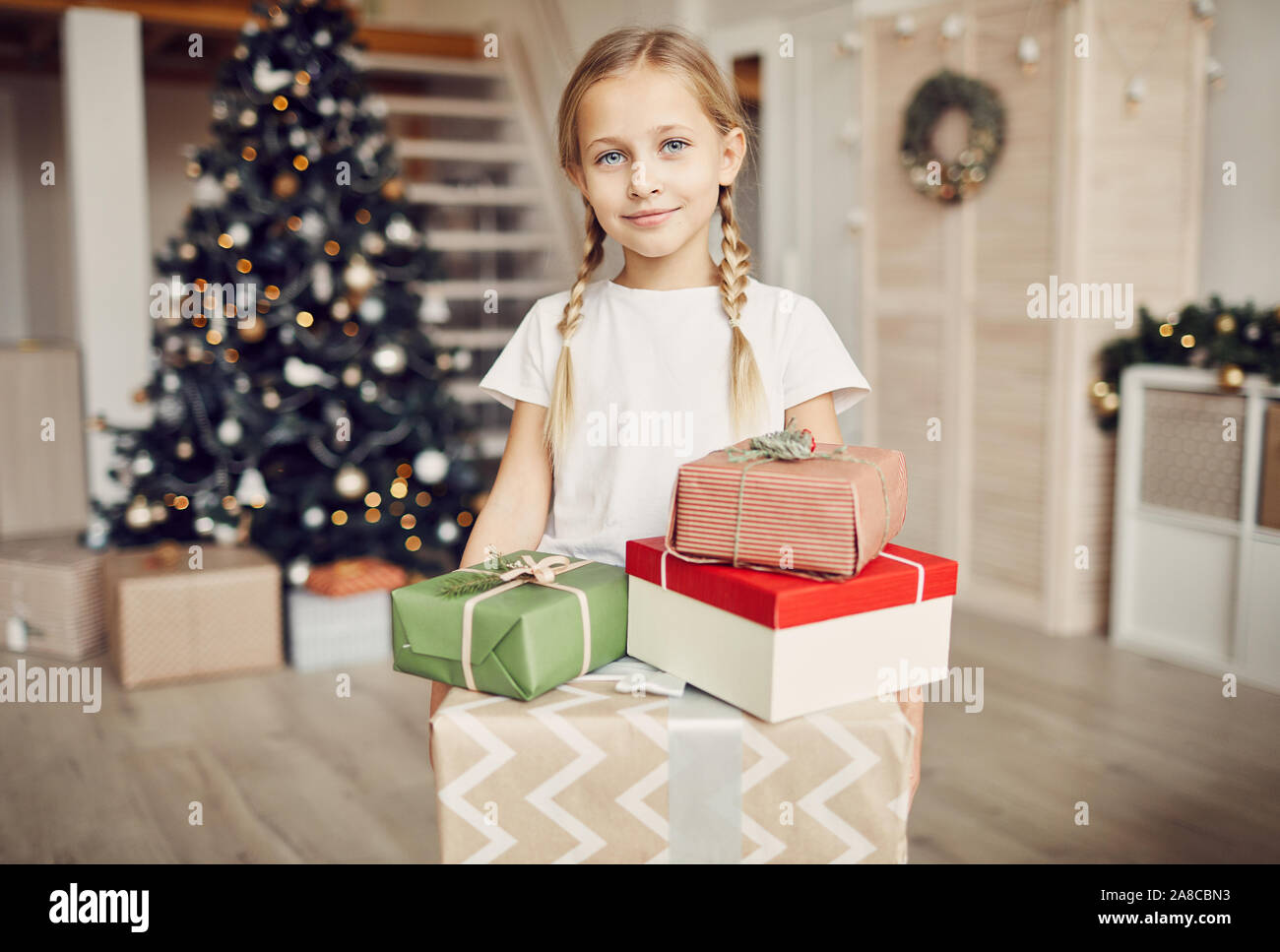 Portrait de petite fille aux cheveux blonds looking at camera while holding gift boxes elle les obtenir du père Noël pour Noël Banque D'Images