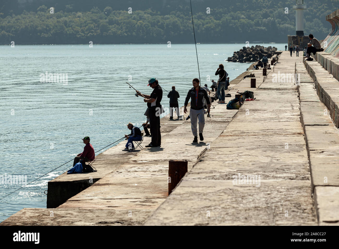 Varna, Bulgarie - 30 septembre 2014 : les pêcheurs sont sur le brise-lames en béton dans la région de Varna, port de lumière arrière photo silhouette Banque D'Images