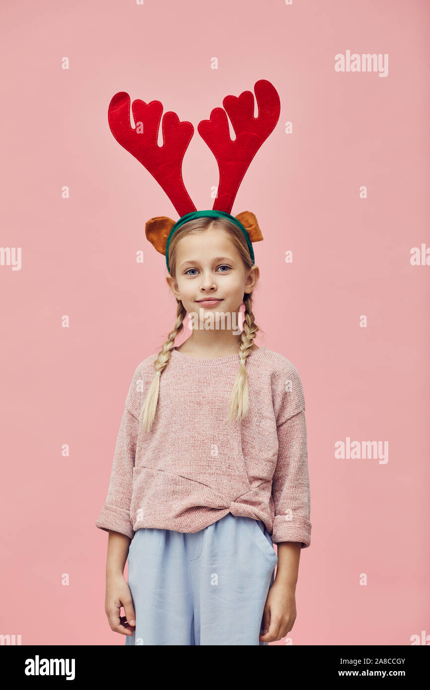 Portrait of cute little girl wearing bois de cerf et à la caméra à plus de fond rose Banque D'Images