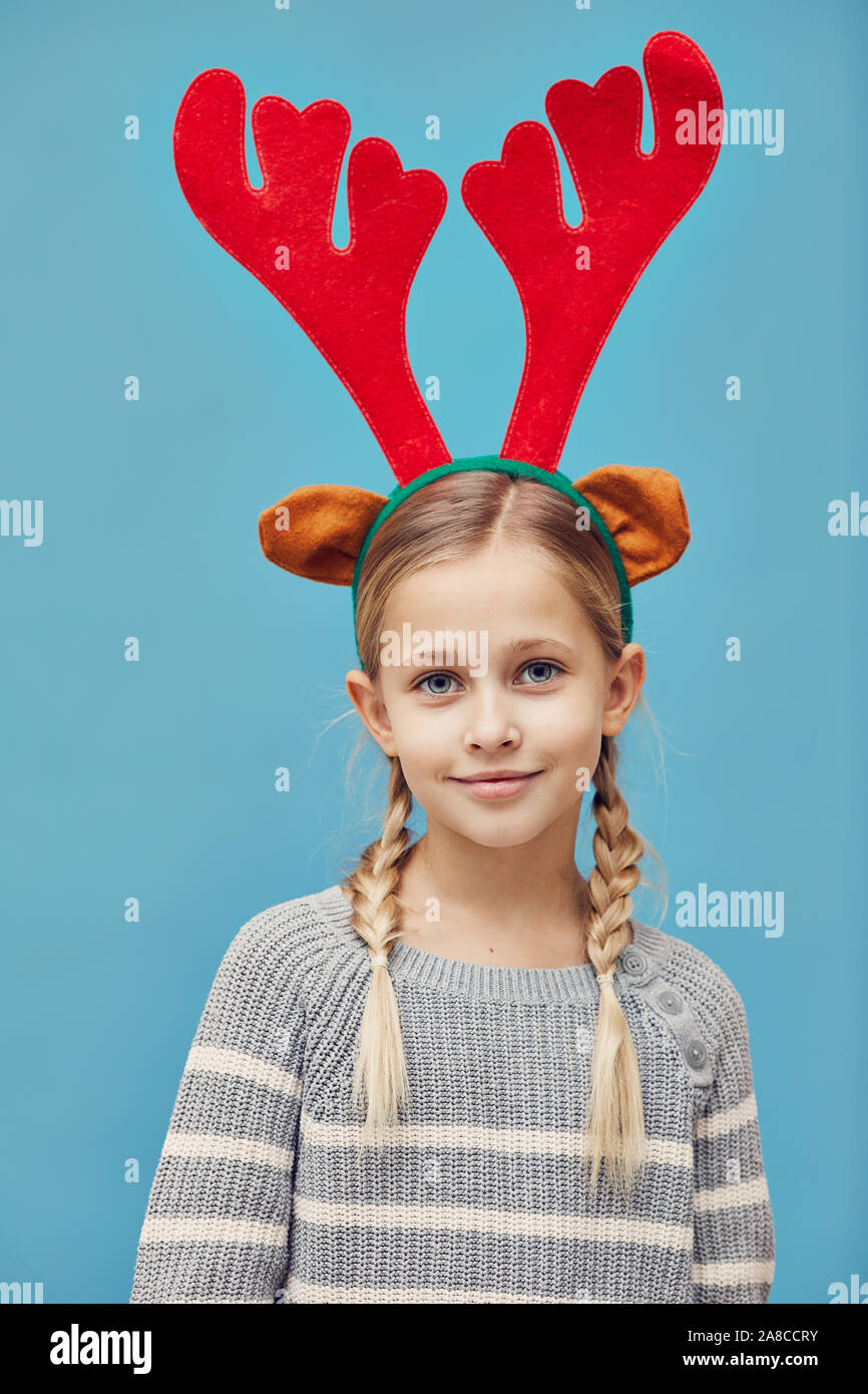 Portrait de petite fille en bois de cerf rouge à la caméra tout en se tenant au-dessus le fond bleu Banque D'Images