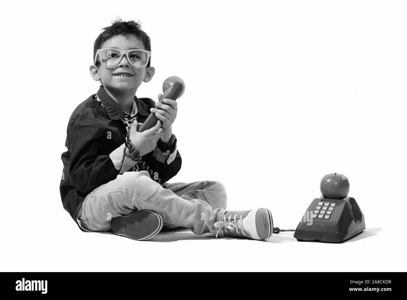 Studio shot of cute happy boy smiling, vieux téléphone tout en regardant vers le haut Banque D'Images