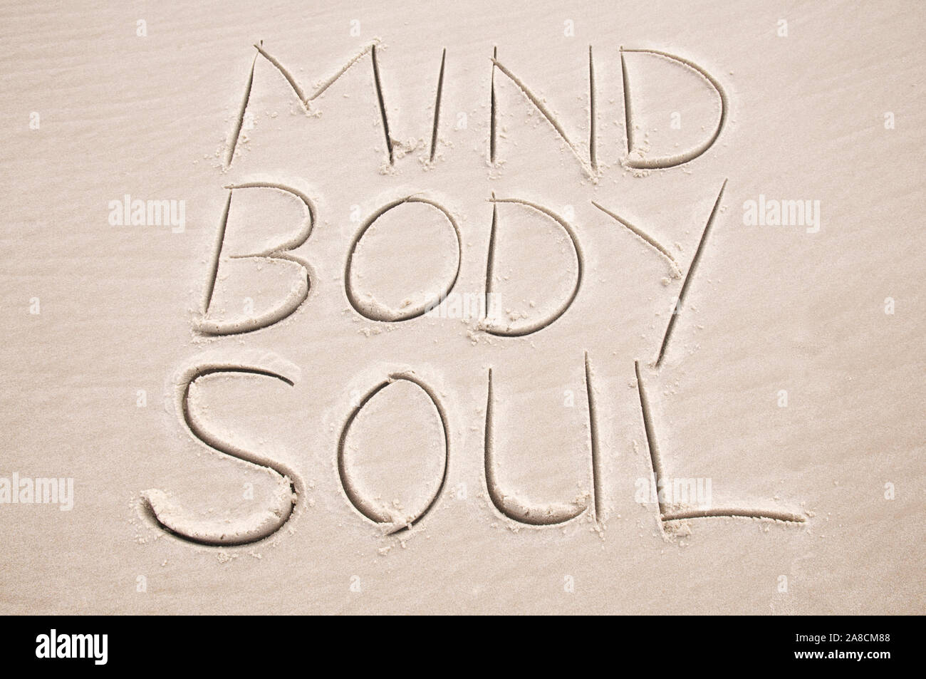 Message holistique de guérison manuscrit dans le sable lisse épeler Corps D'Esprit et âme sur la plage Banque D'Images