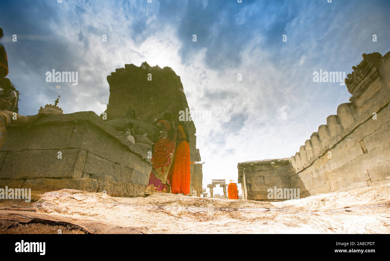 Image abstraite de deux femmes debout à côté d'une statue de serpent avec Shivling vu du 16ème siècle construit Lepakshi Veerabhadra Temple, Inde. Banque D'Images