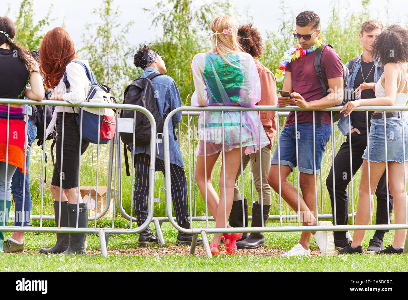 Groupe de jeunes amis en attente derrière les cordons à l'entrée du site du Festival de Musique Banque D'Images