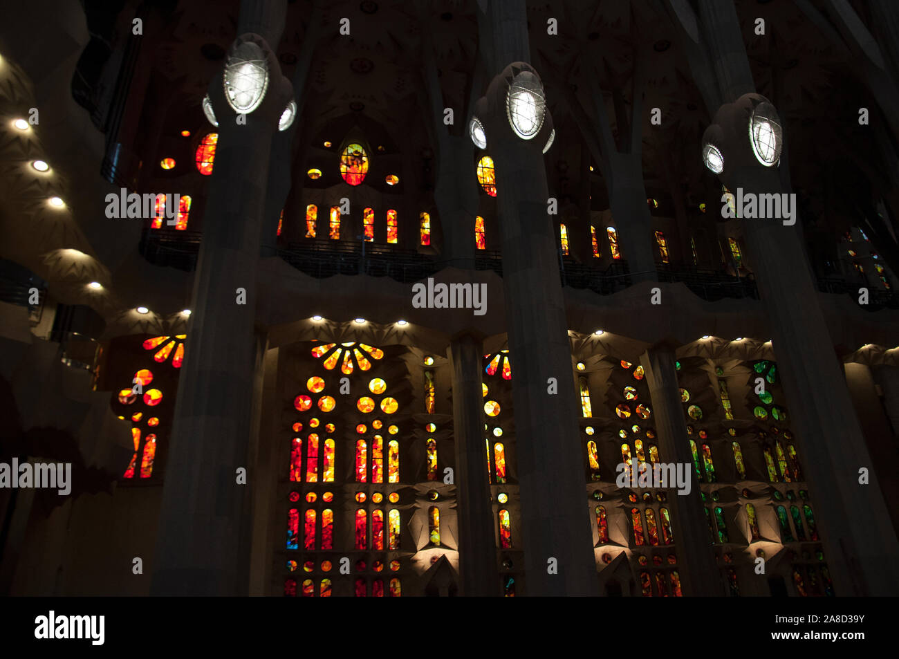 Sagrada Familia - intérieur. Rangées de grands vitraux de couleurs chaudes et de hauts piliers. Banque D'Images