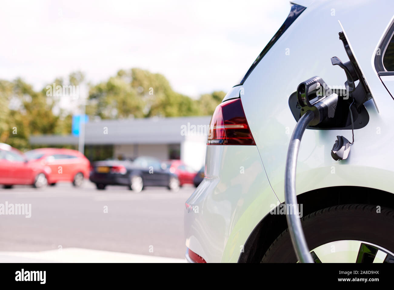 Câble d'alimentation de voiture électrique de charge à l'extérieur dans le parking de supermarché Banque D'Images