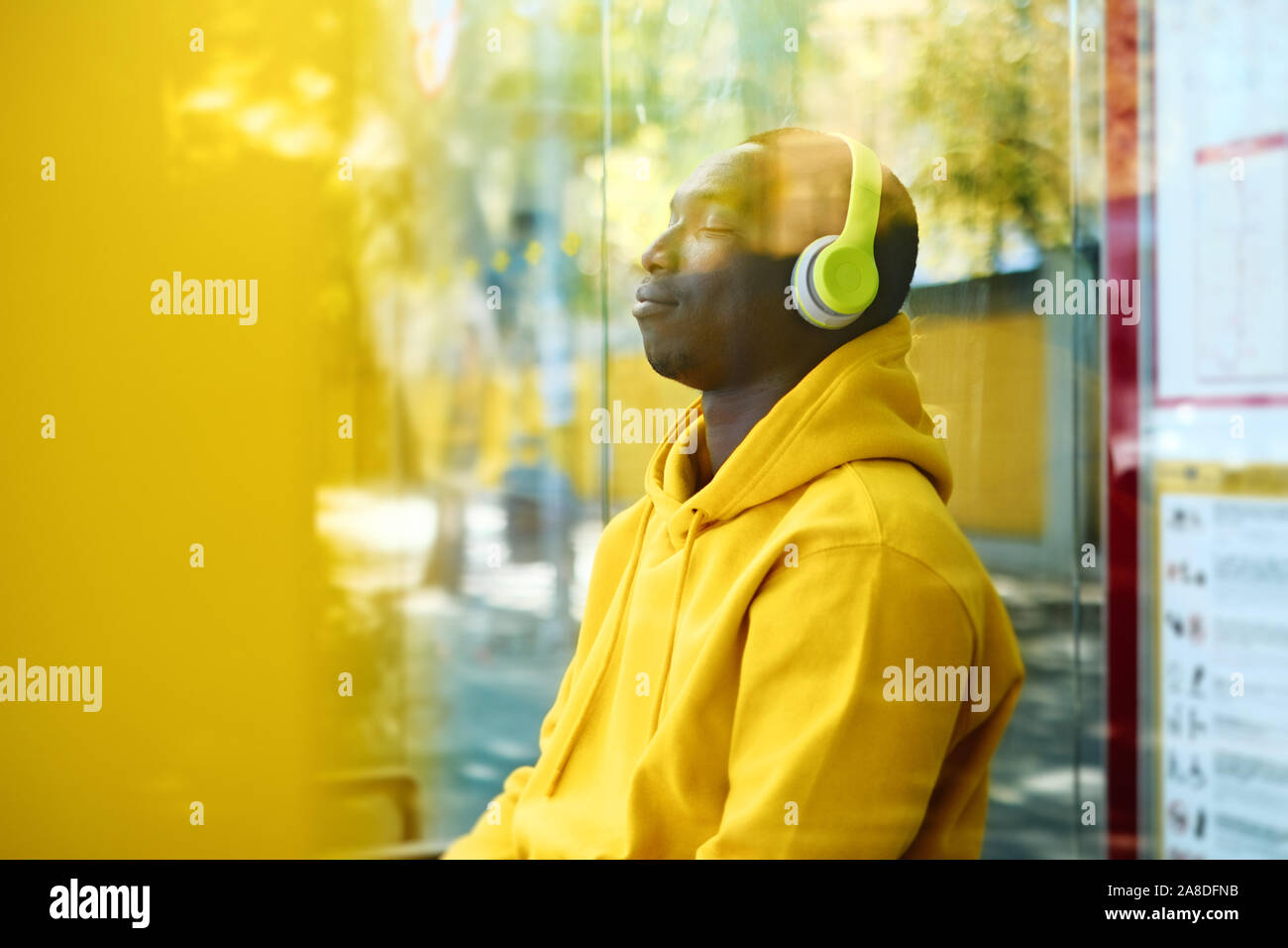 Jeune homme africain d'écouter de la musique à l'arrêt de bus Banque D'Images
