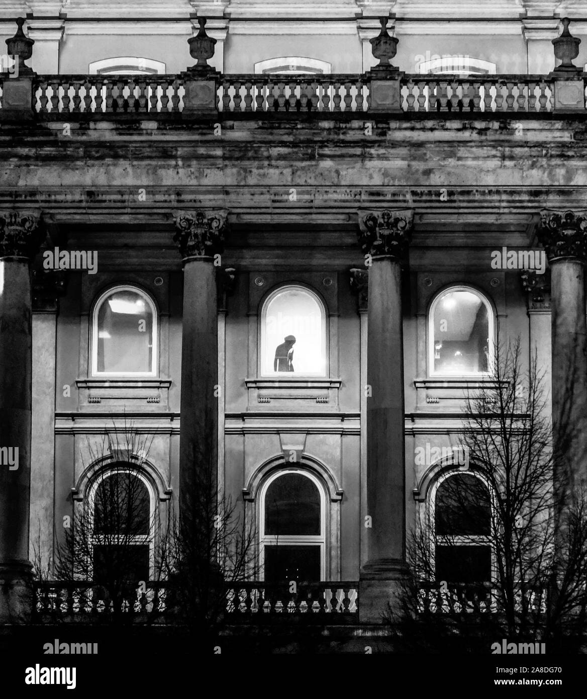 Photo en noir et blanc de windows et les colonnes du château de Buda avec silhouette de femme dans une des fenêtres. Banque D'Images