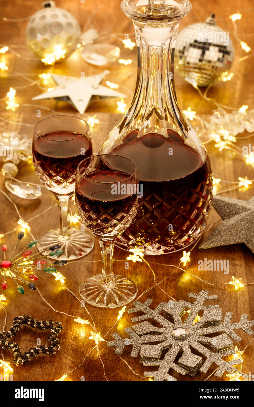 Une carafe de port et verres de cristal avec des lumières de Noël, Décorations de Noël et d'étoiles d'argent, sur une table en bois Banque D'Images