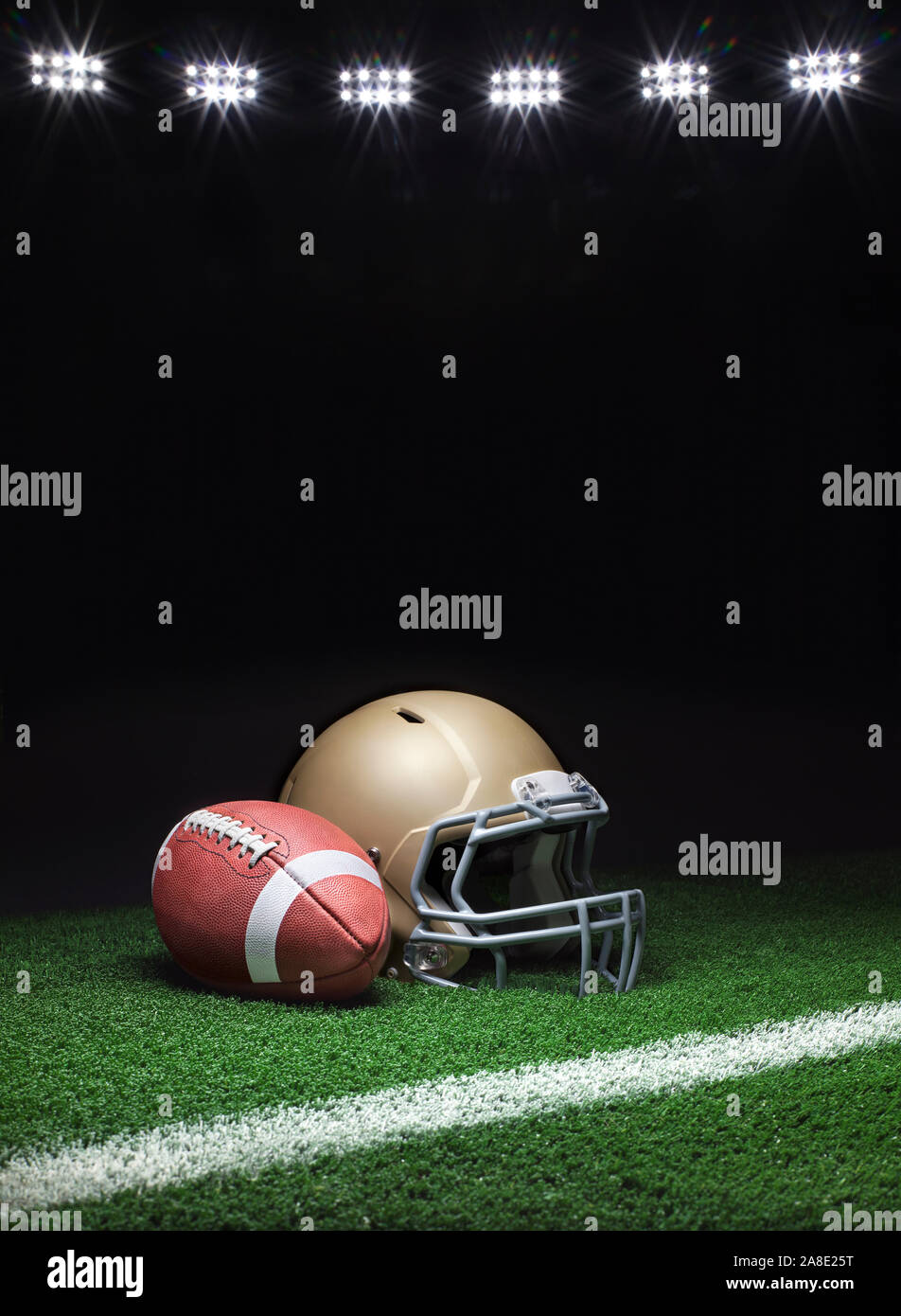 Un portrait d'un casque de football d'or avec un ballon de football sur une pelouse avec bande et un arrière-plan sombre avec des lumières du stade Banque D'Images