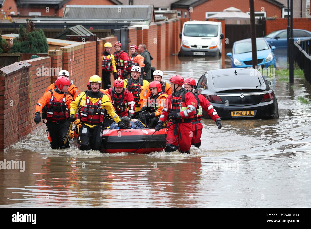 Les membres du service d'incendie et de sauvetage de tirer un bateau gonflable qui a été utilisé pour sauver les habitants piégés par l'inondation dans la région de Doncaster, dans le Yorkshire, comme certaines parties de l'Angleterre a connu un mois de pluie en 24 heures, avec des dizaines de personnes secourues ou forcés d'évacuer leurs maisons, d'autres coincés la nuit dans un centre commercial et des plans de voyage jeté dans le chaos. Banque D'Images