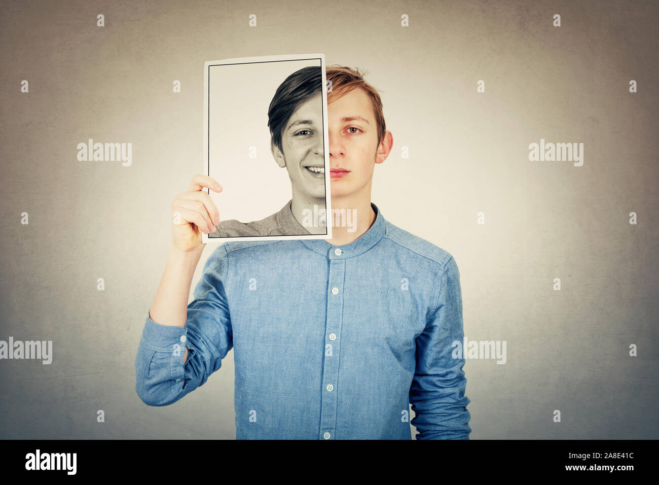 Faux portrait d'un adolescent garçon triste de se cacher la moitié à l'aide d'un feuille de papier d'impression photo avec un faux professionnels de l'émotion. Masque pour cacher la véritable expression, Banque D'Images