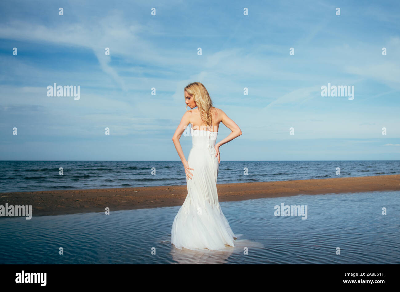 Portrait of young blonde bride restant entre l'eau, regardant vers le bas Banque D'Images