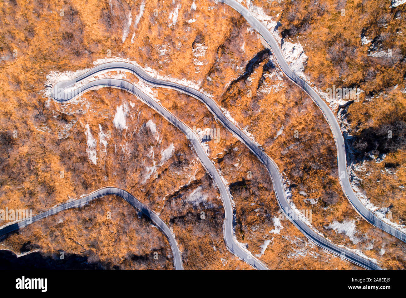 Vue aérienne de la route sinueuse de montagne en automne ou en hiver. Paysage avec les prés jaunes d'herbe sèche et étroite route asphaltée. Vue d'en haut. Banque D'Images