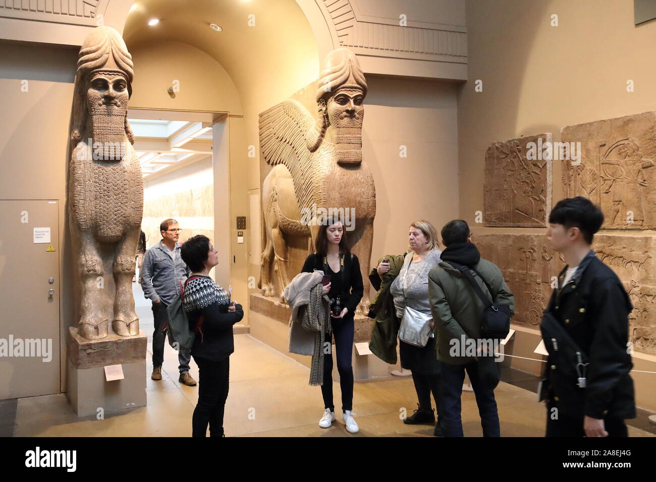 Visiteurs en face de taureaux ailés de Khorsabad assyrienne au British Museum, London, UK Banque D'Images