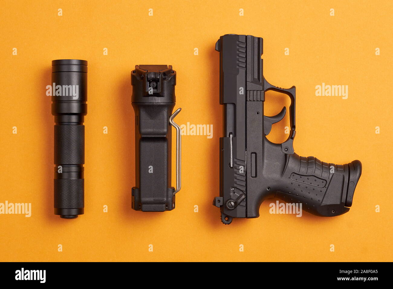 Rapport d'auto-défense - pistolet, le gaz poivré et lampe tactique sur fond  orange Photo Stock - Alamy